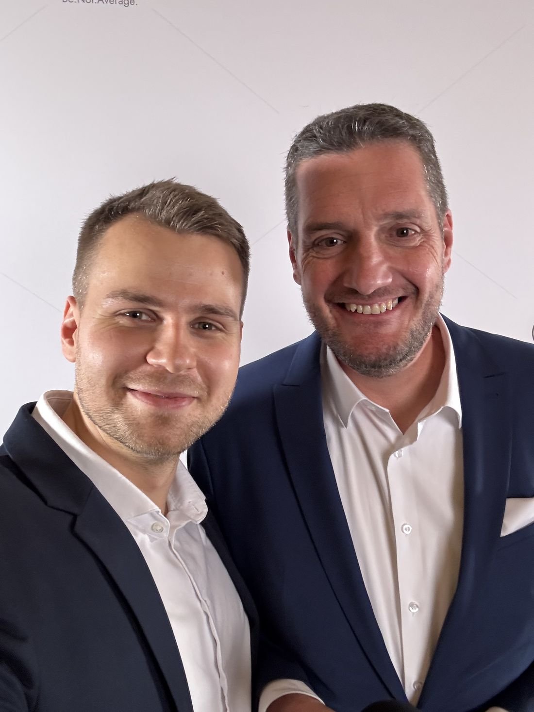 Christoph Billmaier und ein Mitglied nebeneinander vor der Fotowand.