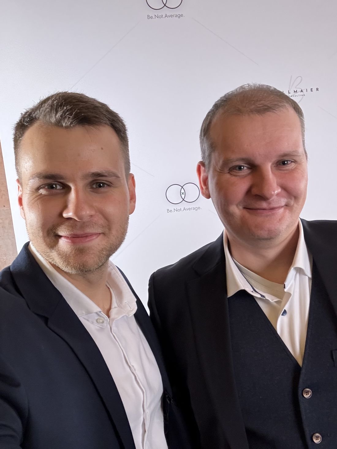 Christoph Billmaier mit zwei Mitgliedern vor der Fotowand.