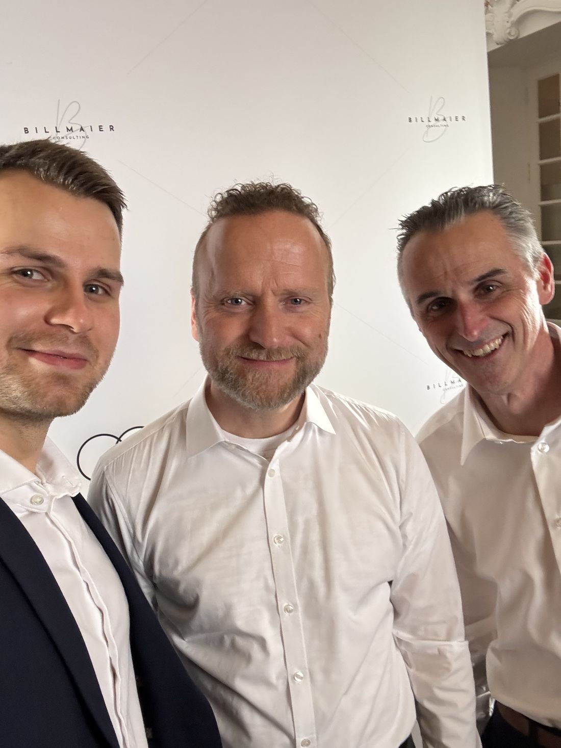 Christoph Billmaier mit einem Mitglied vor der Fotowand von Be.Not.Average.